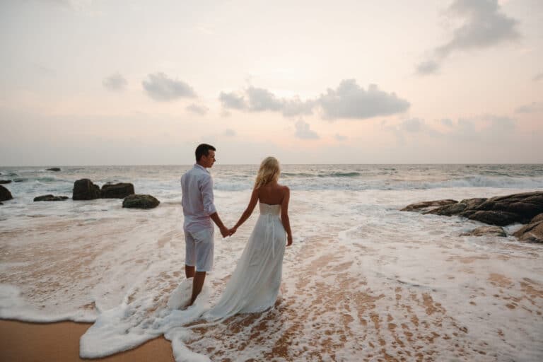 A just married couple stands in the ocean after planning their Hawaii wedding