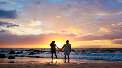A couple holding hands on the beach in Kauai to celebrate Valentine's Day with a Hawaii vacation
