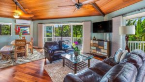 The living room with couches, a TV, and large windows at a Princeville vacation rental