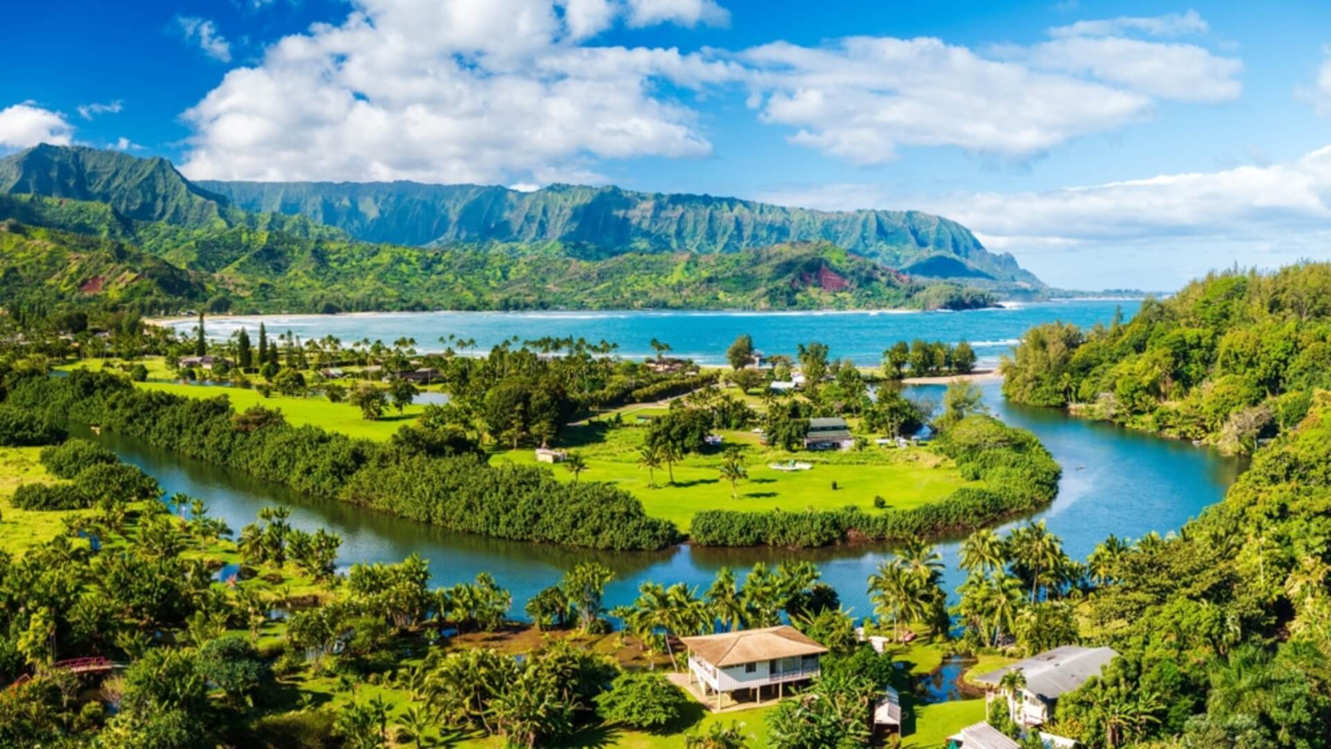 A sunny day on Kauai overlooking the island's mountains, lush greenery, and ocean waters