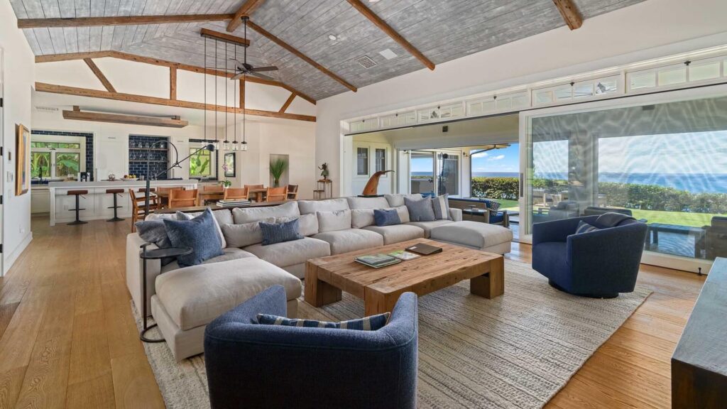 The spacious living room with ocean views and access to a private covered lanai at a luxur vacation home on Kauai