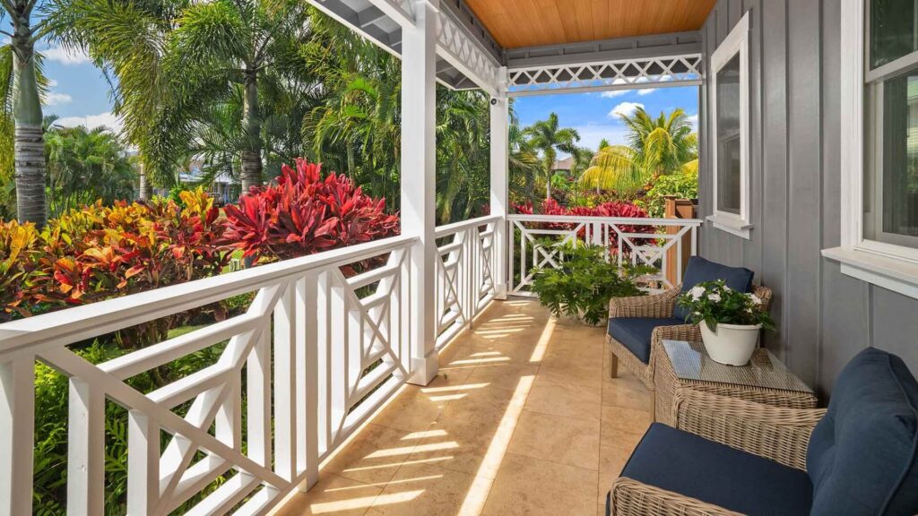 The large covered lanai with a cozy seating area and garden views at a vacation home in Poipu