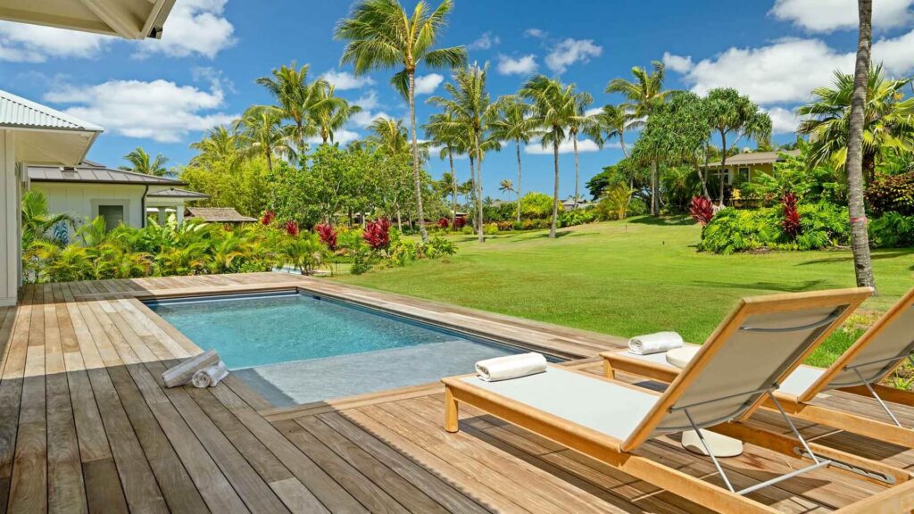Lounge chairs overlooking a pool and garden views at Kukuiula Makai Cottage #22