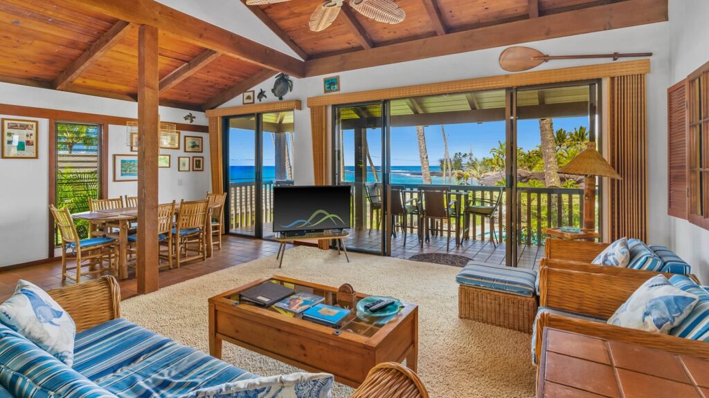 A living room with comfortable seating and a television with access to a private lanai with ocean views at Nihi Kai Villas #200